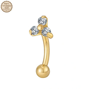 Close das 3 zircônias cravadas no piercing curvo banana dourado de titânio sobre fundo branco