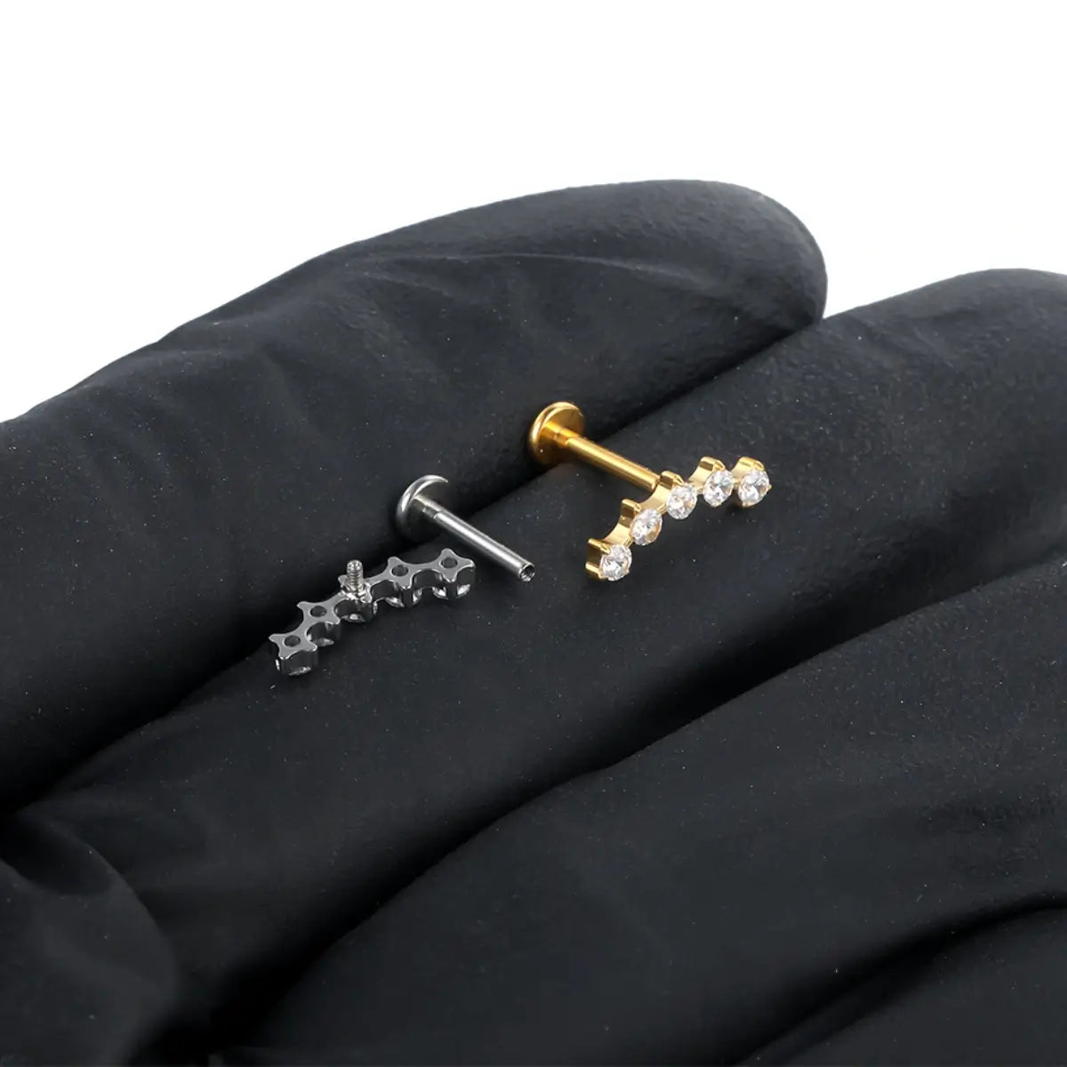 Piercings labret de titânio com cluster espaçado de 5 zircônias em prata e dourado sobre tecido escuro