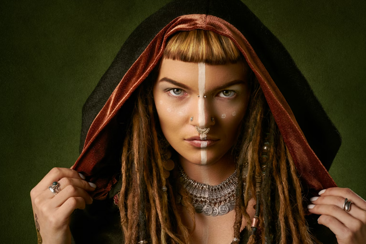 imagem apresenta o retrato de uma mulher com uma estética étnica e mística, focada na expressão facial e no simbolismo visual.
