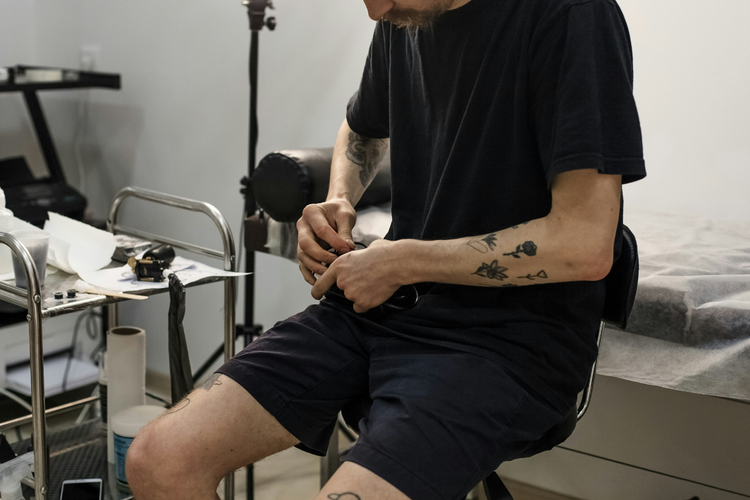 retrata um profissional, provavelmente um tatuador ou piercer, em um estúdio.