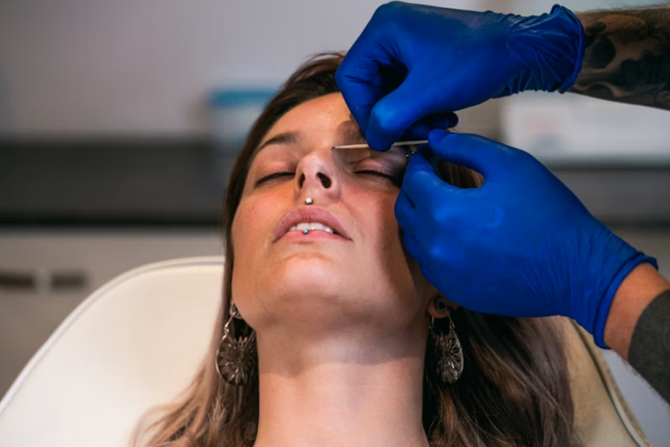 A imagem que retrata o procedimento de piercing foca na precisão e no cuidado técnico dentro de um ambiente profissional de estética.