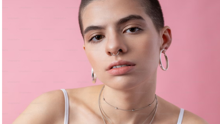 Uma pessoa com piercings prateados nas orelhas e nariz