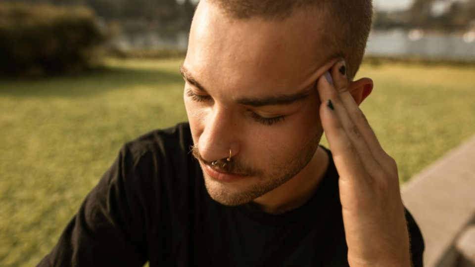 Homem com piercing no septo com expressão de dor — referência visual para dor no piercing pós-procedimento