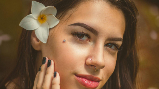 Piercings e Modificações: A jovem exibe uma composição de joias que inclui:  Um Microdermal (ou piercing de superfície) na maçã do rosto, logo abaixo do olho.  Um pequeno ponto de luz no nariz (nostril).  Um Septo (argola discreta).