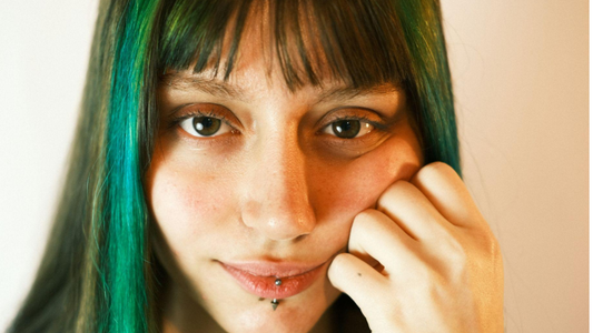 Imagem mostra uma pessoa com cabelos coloridos e piercing nos lábios