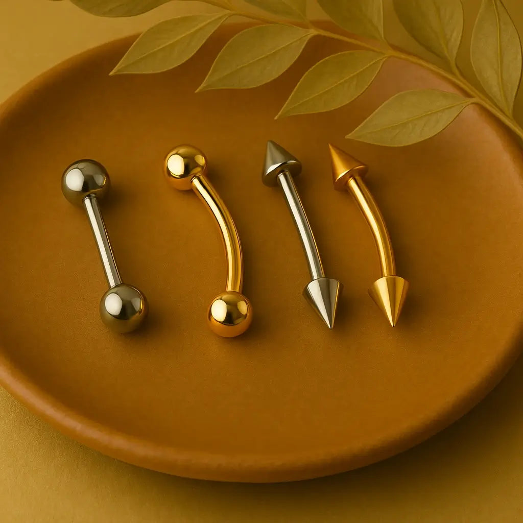 Dois piercings barbell prateado e dourado, nos modelos curvo e reto, sobre fundo marrom