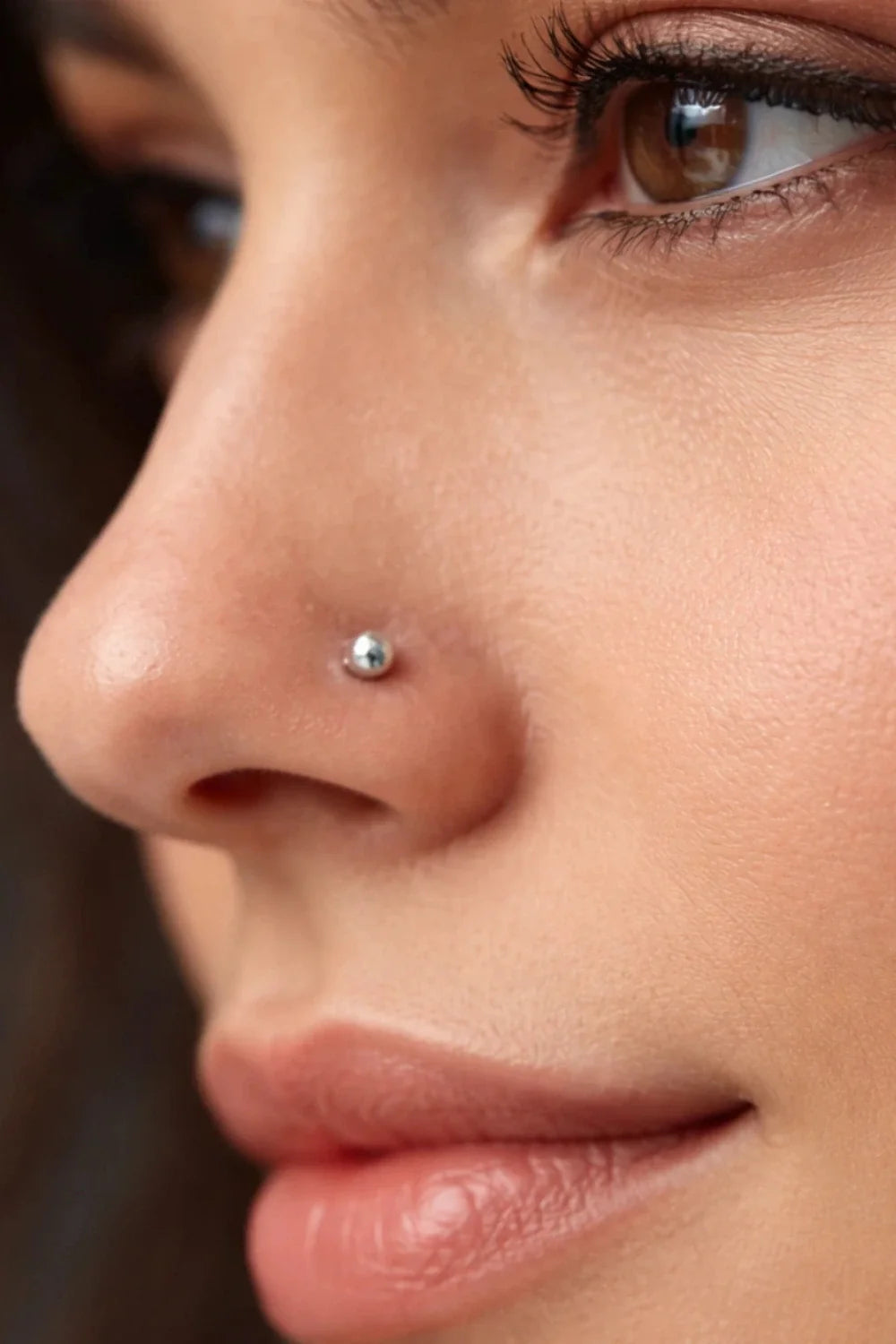 Piercings para nariz: modelo feminina de perfil com piercing labret de titânio com bolinha prata na lateral do nariz