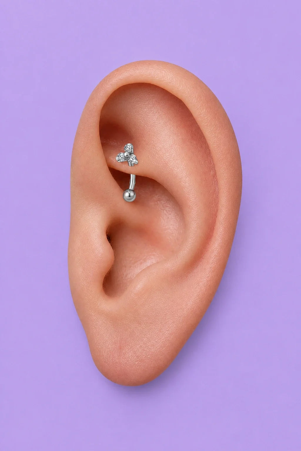 Piercing rook em titânio G23, barbell curvo com duas bolinhas metálicas prateadas, aplicado na cartilagem interna da orelha.