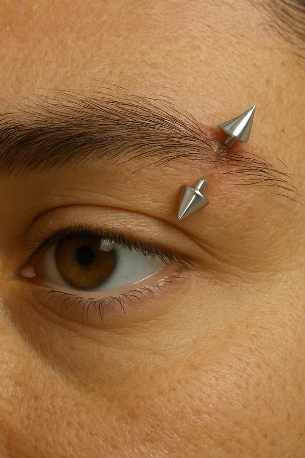 Piercing para sobrancelha em aço cirúrgico, modelo barbell com spike prateado.