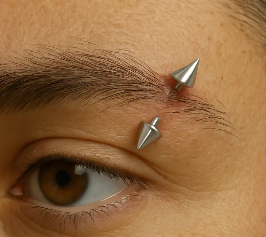 Piercing para sobrancelha em aço cirúrgico, modelo barbell com spike prateado.