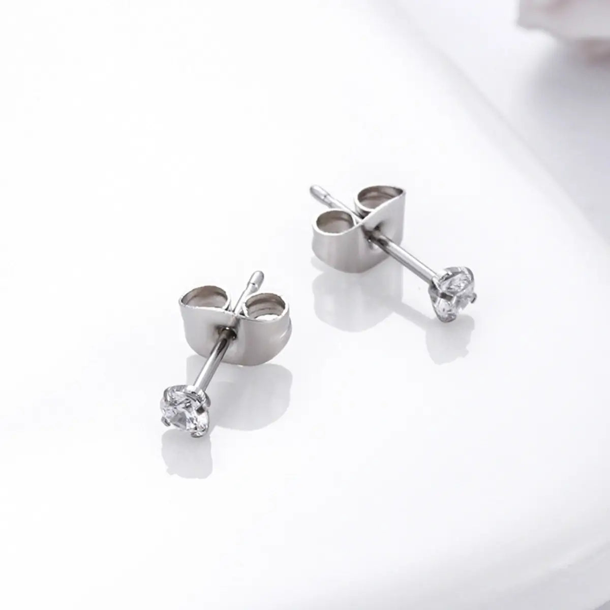 Brincos ponto de luz prateados de aço cirúrgico com zircônia cravada em close sobre fundo branco