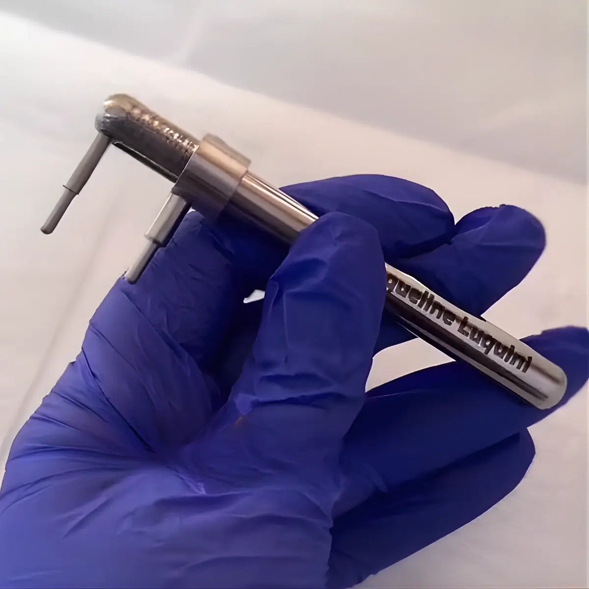 Mão com luva azul segurando piercímetro marcador corporal mostrando escala de medição