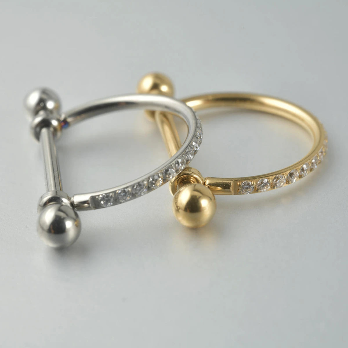Piercing barbell com arco cravejado em zircônias nas cores prata e dourado