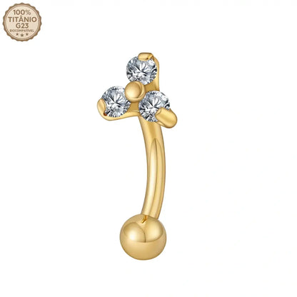 Close das 3 zircônias cravadas no piercing curvo banana dourado de titânio sobre fundo branco
