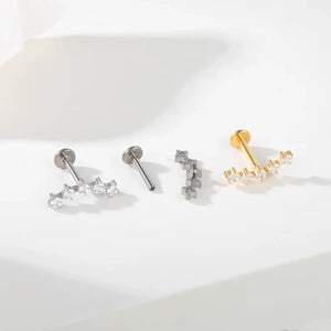 Variações de piercings labret de titânio com cluster espaçado de 5 zircônias nas cores prata e dourado sobre fundo claro