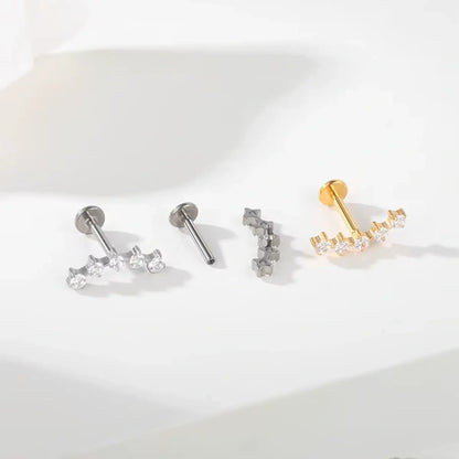 Variações de piercings labret de titânio com cluster espaçado de 5 zircônias nas cores prata e dourado sobre fundo claro