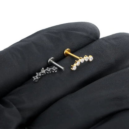 Piercings labret de titânio com cluster espaçado de 5 zircônias em prata e dourado sobre tecido escuro