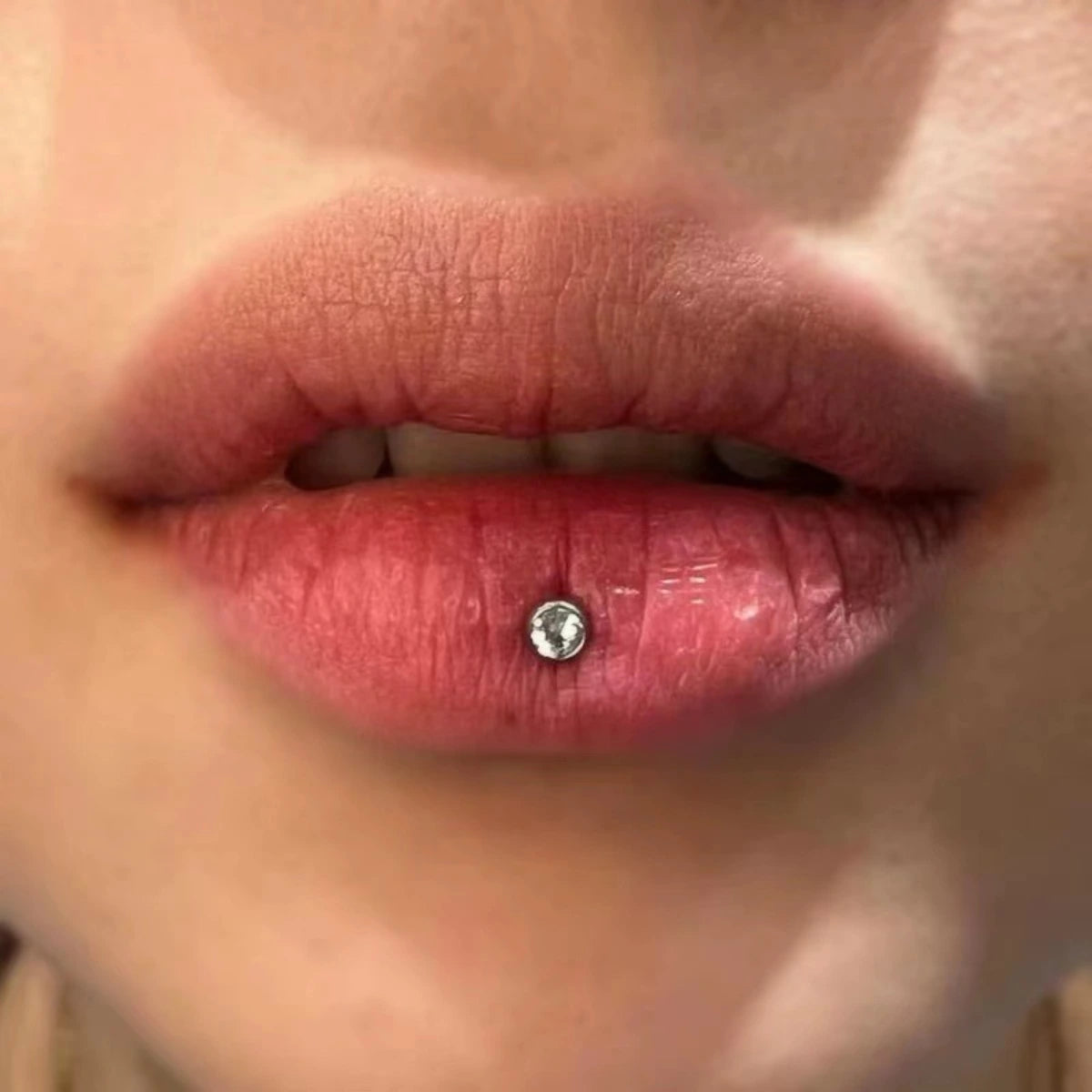 Piercing labret com zircônia aplicado abaixo do lábio, com brilho discreto e elegante